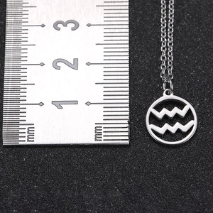 Macro shot showing 20mm round cutout Aquarius zodiac pendant with a metal ruler
