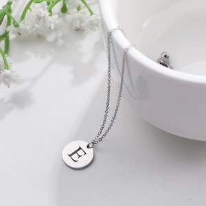 Detailed shot of silver stainless steel letter E round pendant on a fine link chain