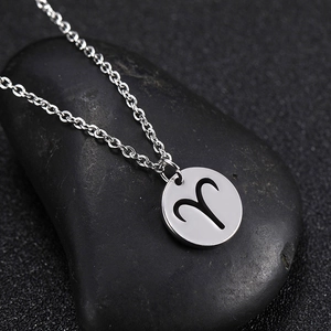 Close-up of silver Aries zodiac necklace with hollow circular pendant on black stones
