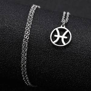 Macro view of a polished silver Pisces constellation pendant with intricate hollow design