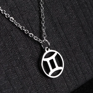 Macro detail of silver Gemini zodiac pendant on a stainless steel link chain