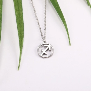 Detail of silver Sagittarius zodiac pendant with hollow circular design on thin cross chain