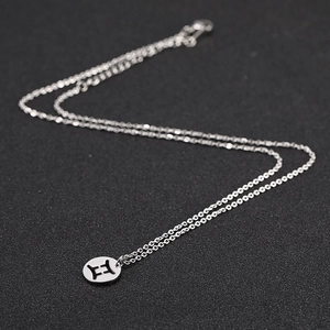 Macro shot of silver stainless steel Gemini zodiac pendant with intricate cutout detail