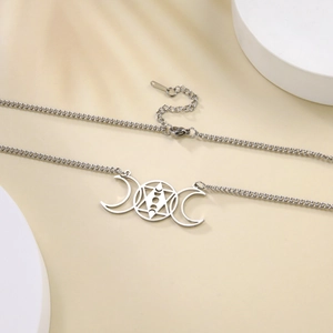 Macro detail of silver stainless steel triple moon and hexagram pendant necklace