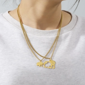 Detailed view of layered gold elephant pendants on a stainless steel chain worn by model