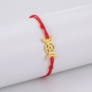 Nahaufnahme eines roten geflochtenen Armbands mit goldenem Dreifachmond- und Pentagramm-Anhänger