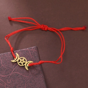 Detailaufnahme des roten Kordelarmbands mit goldenem Dreifachmond und Pentagramm