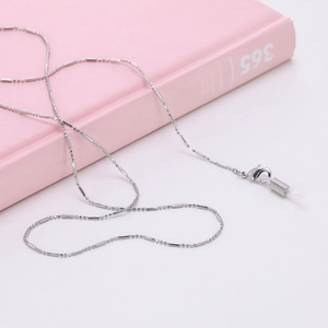 Détail de la chaîne à lunettes argentée avec boucles silicone sur livre rose