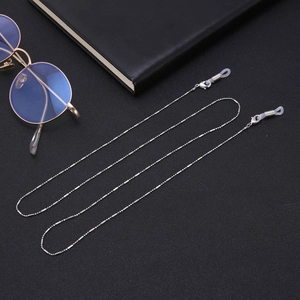 Détail d'une chaîne à lunettes perlée argentée avec boucles en silicone sur fond noir