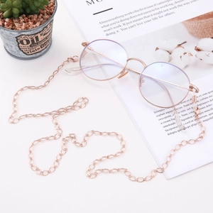 Detail of rose gold round glasses and hollow diamond link copper chain on a magazine
