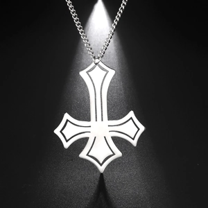 Macro detail of polished stainless steel inverted cross pendant on a dark background