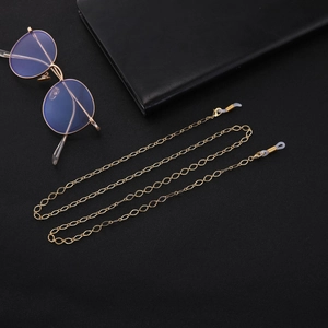 Detail of golden hollow diamond link eyewear chain with silicone loops on black background