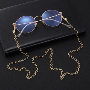Detail of gold metal glasses chain with non-slip silicone loops on black leather notebook