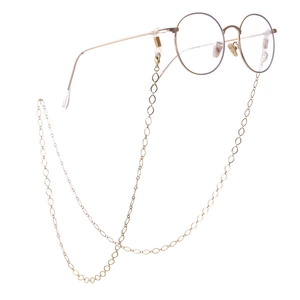 Golden hollow diamond mesh eyeglass chain with vintage round metal spectacles on white