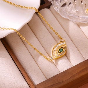 Detail of gold evil eye necklace with green crystal inlay in luxury jewelry box