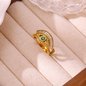 Close-up of a gold evil eye ring with a green center stone and white zircon accents
