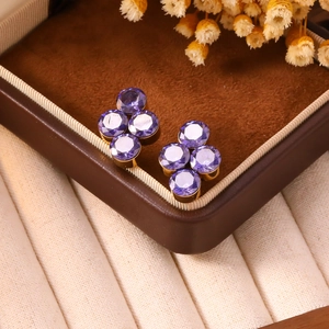 Dettaglio degli orecchini a trifoglio viola placcati oro in una scatola regalo di lusso