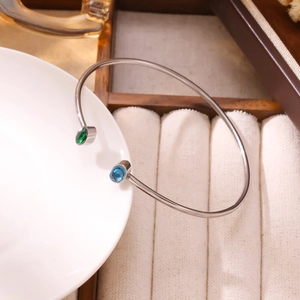Dettaglio del bracciale argento aperto con pietre preziose verdi e blu su portagioie
