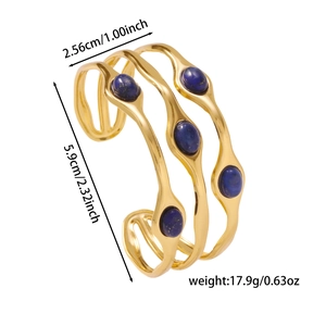Detail eines offenen, 18K vergoldeten Armreifs mit Wellendesign und blauen Edelsteinen