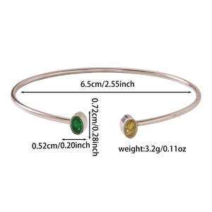 Dettaglio del bracciale aperto color argento con pietre verdi e gialle incastonate