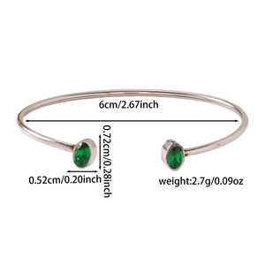 Macro di un bracciale rigido argento lucido con due pietre di zircone verde ovale