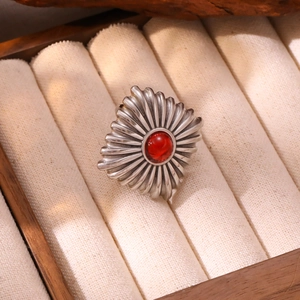 Détail macro d'une bague vintage argentée avec motif soleil et cristal rouge rond