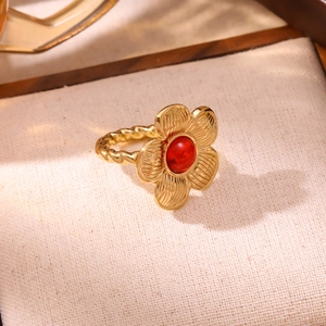 Detail of a vintage 18K gold floral ring with a red stone and twisted rope band texture