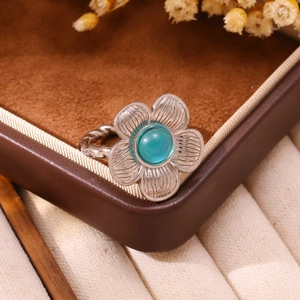 Macro detail of silver flower ring with turquoise stone and twisted rope band design