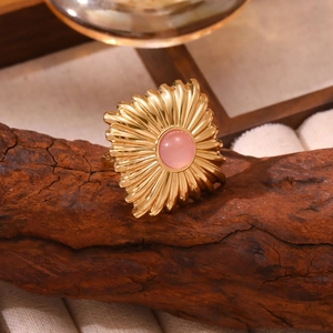 Détail macro de la bague vintage dorée avec cristal rose et motif soleil sur bois