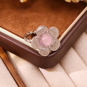 Detail of flower shaped ring with pink stone inlay and textured silver petals on vintage box