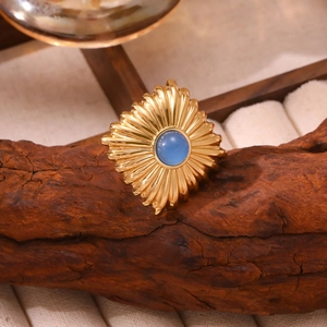 Macro d'une bague vintage dorée avec pierre bleue et motif soleil rayonnant