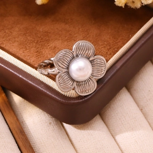 Detail of silver vintage flower ring with pearl inlay and textured rope band