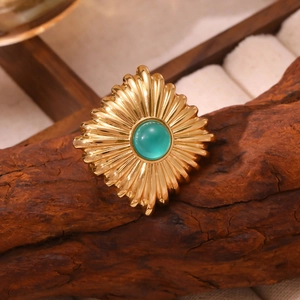 Bague vintage dorée avec pierre verte ronde posée sur une surface en bois naturel