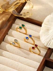 Gros plan de quatre bagues vintage dorées avec pierres colorées sur une boîte à bijoux en bois