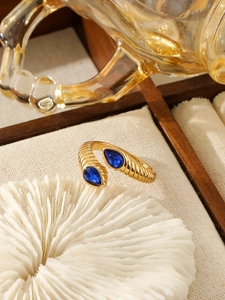 Gros plan détaillé d'une bague nervurée dorée vintage avec pierres en goutte bleues