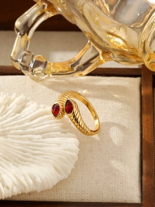 Macro détaillée d'une bague dorée torsadée avec deux pierres de zircon rouge poire