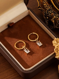 Detail von 18K Gold Creolen mit Smaragdschliff-Kristallen in einer edlen Schmuckbox