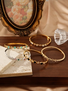 Detail of gold and silver bangles with colorful enamel hearts and zircon inlays