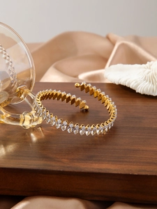 Dettaglio degli zirconi taglio marquise su un bracciale rigido dorato regolabile