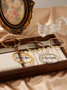 Detailed display of colorful zircon and enamel inlay stainless steel bangles on wood rack