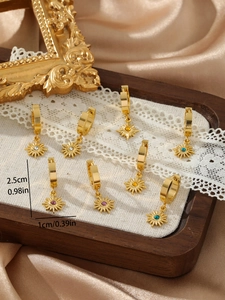 Detail of vintage gold sunflower earrings with colorful zircon stones on white lace