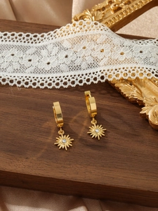 Close-up of vintage gold sunburst earrings with sparkling zircon on a silk background