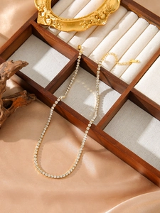 Gros plan du collier tennis doré serti de zircons sur soie avec détail du poinçon S925