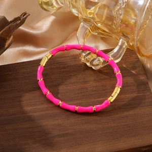 Detail of bamboo joint style gold bangle with pink enamel on dark wood and silk