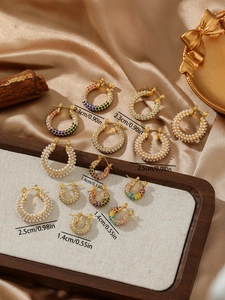Detalle de pendientes dorados con perlas y circonitas en tamaños de 2,5 cm, 2,3 cm y 1,4 cm