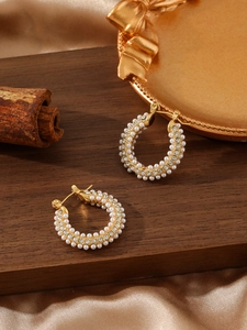 Primer plano detallado de pendientes de aro dorados con perlas y circonitas brillantes