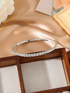 Detailed macro view of a silver tennis bracelet with square-cut cubic zirconia on satin