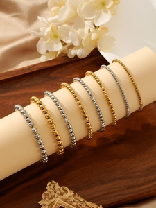 Detail of stacked gold and silver polished metal bead bracelets on a neutral display