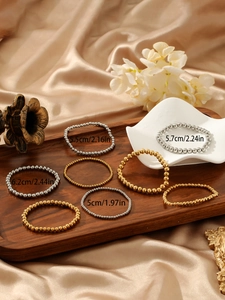 Detailed size display of polished gold and silver beaded elastic bracelets on a tray