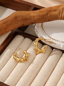 Detailed shot of golden irregular geometric earrings in a natural wood jewelry box